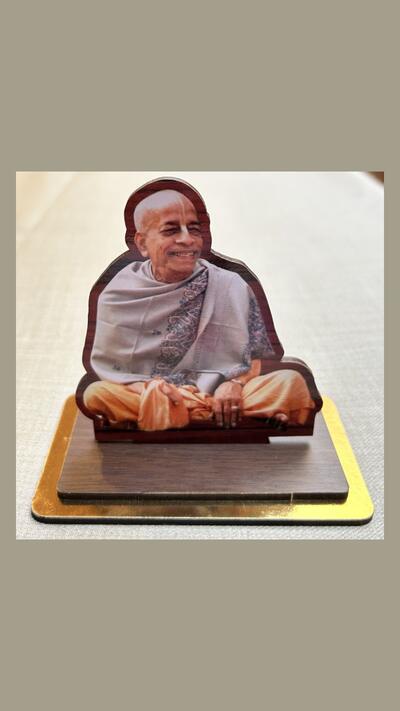 A wooden statue of Prabhupada on a plinth