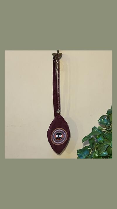 A burgundy-coloured japa bag with the head of Jagannātha