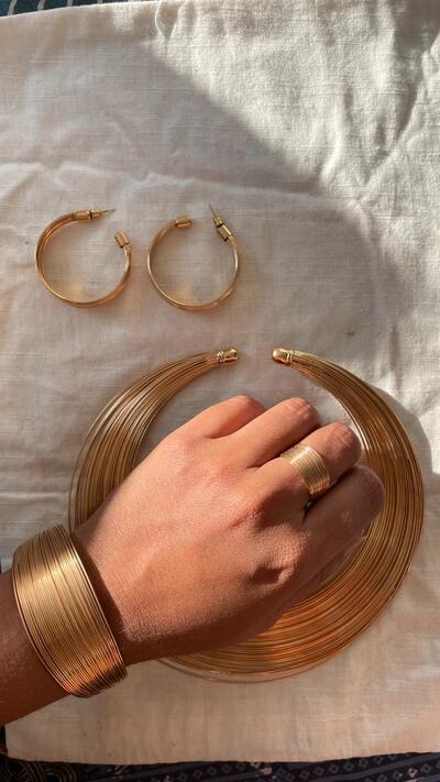 Gold-toned jewellery set of collar necklace, matching hoop earrings, a cuff bracelet, and a ring